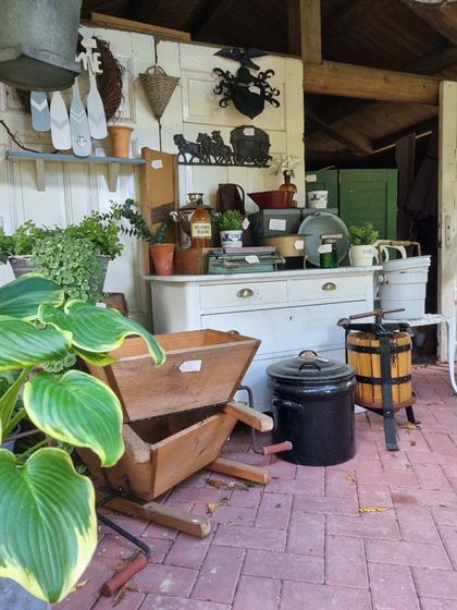 Weiße Anrichte im Gartenhaus mit Pflanzen, Weinpresse und Emaille