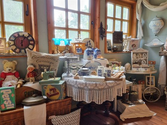 Fensterfront mit blau-weißem Porzellan, Teddybär und alter Kindernähmaschine
