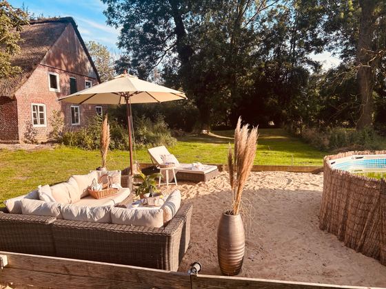 Lounge-Ecke mit Sonnenschirm und Sandfläche am Pool