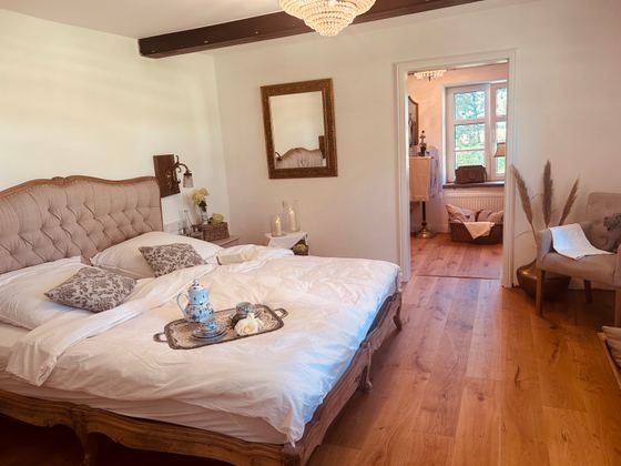 Schlafzimmer mit gepolstertem Bett, Tablett und warmem Abendlicht