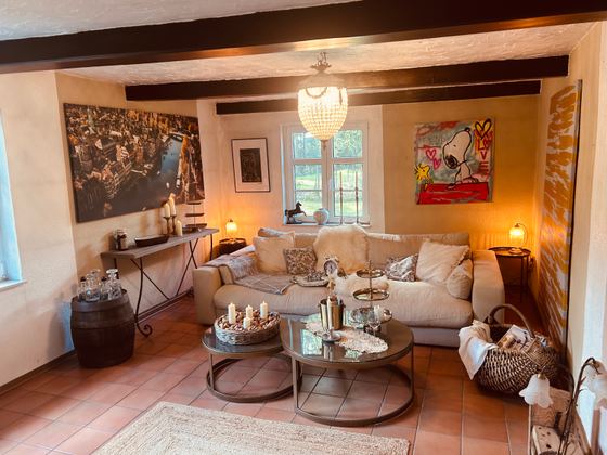 Gestagtes Wohnzimmer mit heller Couch, Kronleuchter und warmem Licht