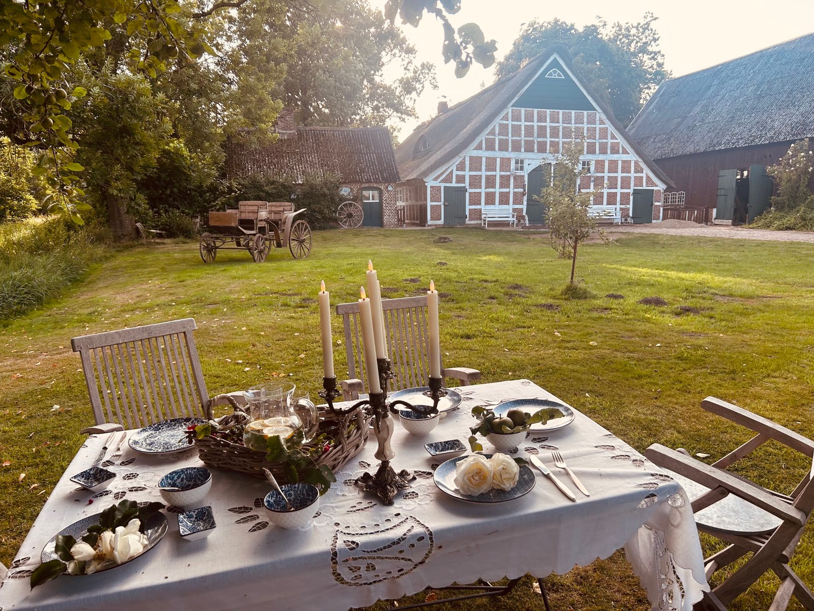 Fachwerkhaus mit festlich gedecktem Tisch und alter Kutsche im Garten